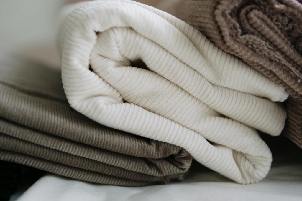 Stack of folded corduroy fabrics in beige and brown, perfect for textile projects.