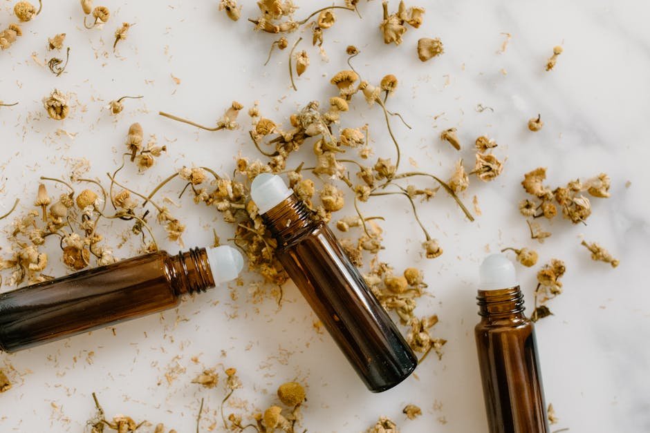 Brown roll-on bottles with dried chamomile flowers on a white background.