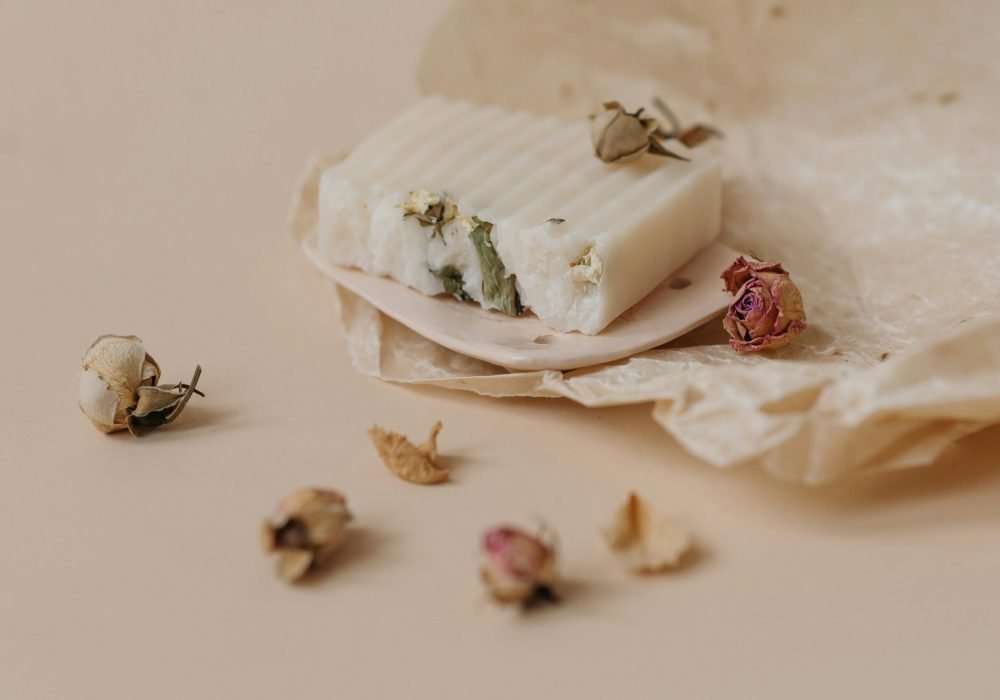 Close-up of artisanal soap with dried flowers on wax paper, eco-friendly product